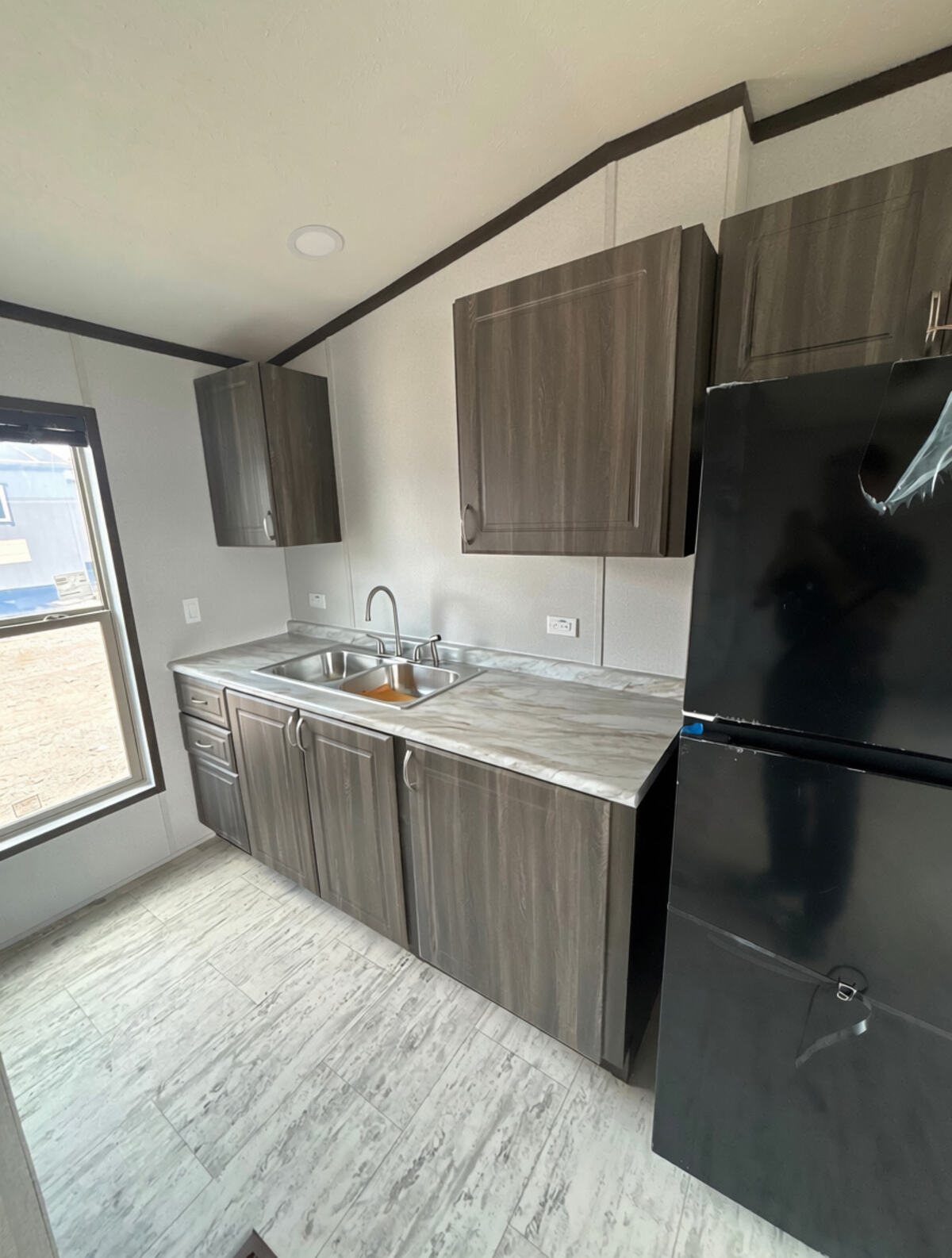 Cocina completa con refrigerador, estufa y gabinetes dentro de una unidad de vivienda H-2A